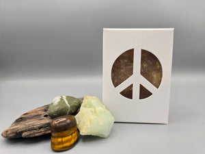 All natural plant based soap scented  amber, frankincense, & clove with tobacco leaf & amber  and housed in a white box with a peace sign cut out surrounded by driftwood and crystals.